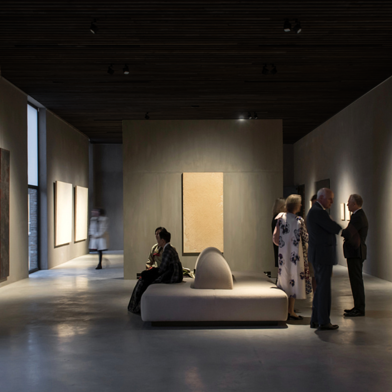 Yumuşak aydınlatmalı minimalist sergi salonu ve ziyaretçiler
